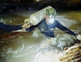 Two Thai Navy Seals battle their way against the current to move diving air tanks deeper into Tham Luang cave