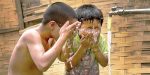 Children cooling off with clean, piped water in Khan Village.